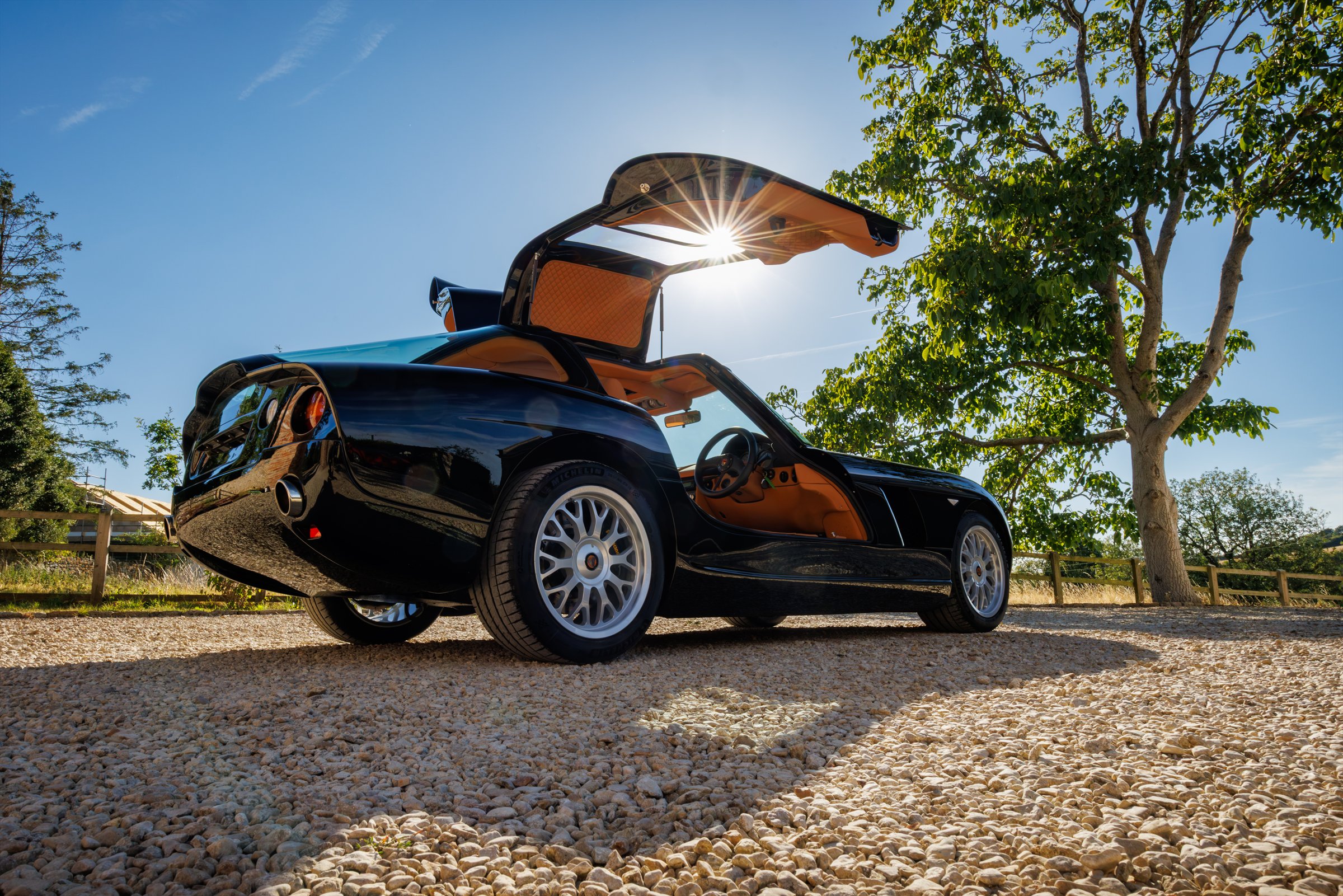 Rear three-quarter view of the full new-build Bristol Fighter with its gullwing door open in sunlight